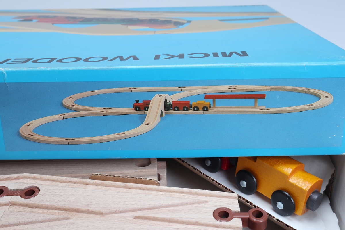 "Micki Combinor", tågset - bestående av rälsbitar, tillverkade av fernissad bok, sammanfogade med plastkopplingar samt ett tågset, bestående av ett lok och tre vagnar. Loket är rött. Vagnarna är gula, gröna och röda. De har kopplingar mellan sig utförda av pålimmade magneter. Rälsen har två parallella utfräsningar som tåghjulen löper i. Rälsen delas upp på följande sätt: sexton böjda delar, två raka, en växelplatta, en station och en bro i två delar. Tågsetet är förpackat i en vit pappkartong med blått lock med bild på. Locket har text på engelska.

Inskrivet i huvudkatalog 1982.