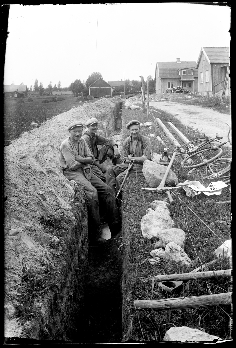 Tre män gräver avloppsdike
