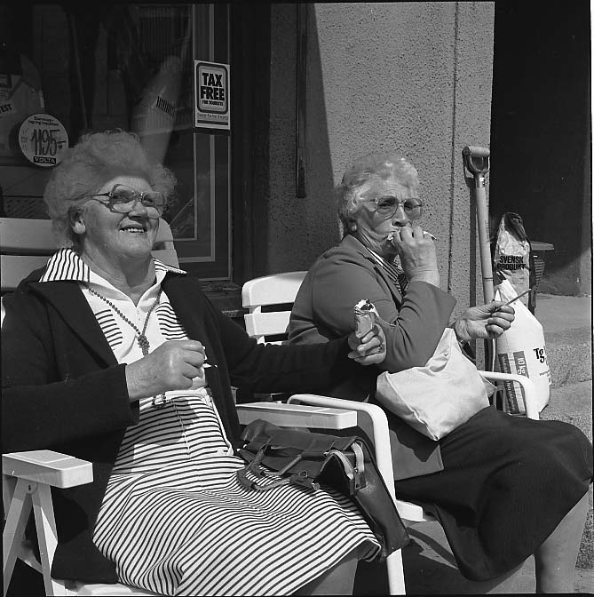 Två okända äldre damer sitter utanför Brahegatan 55 (Palms Järn) och äter glass.