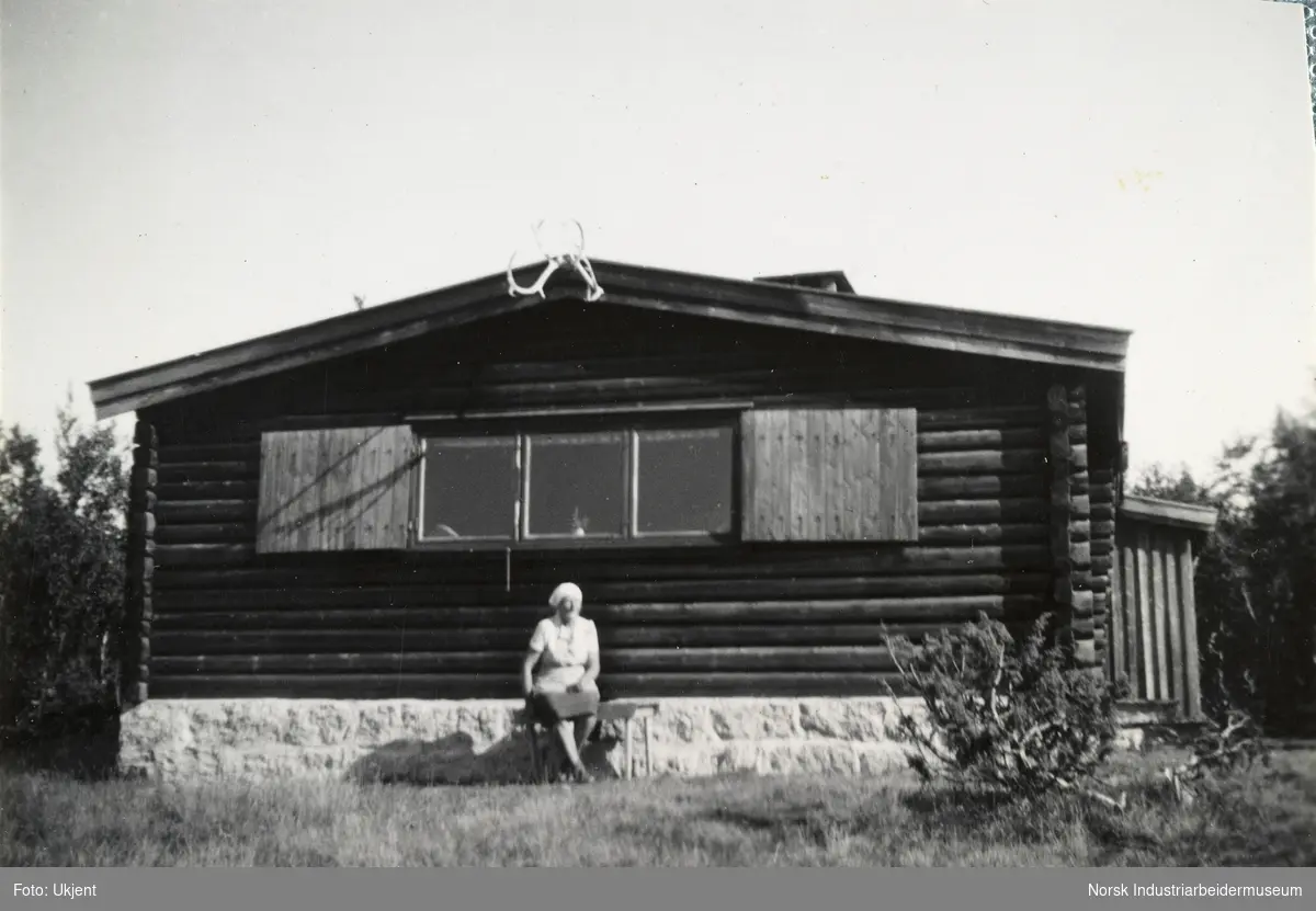 Kvinne sitter på benk utenfor hytte på Grøntorv, Møsstrond