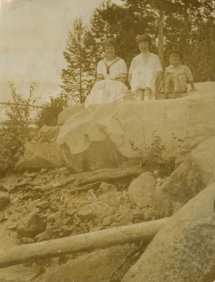 Barn sittandes på en stor sten.