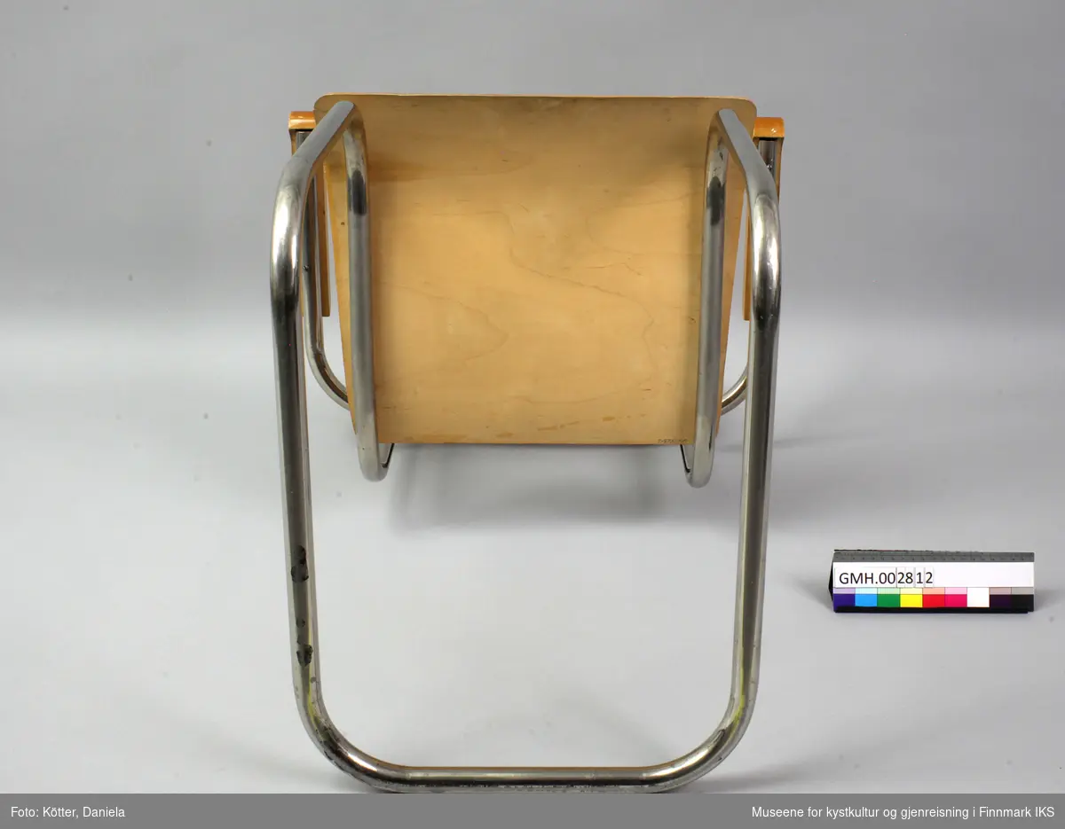 Ramma til stolen er laget av buet stålrør, rørene som holder armlenene, er sveiset på. Den nederste delen som er fotstøtten vender bakover, mens de øvre endene utgjør festen til ryggstøet. Ryggen til stolen består av en transparent lakket finérplate som er buet konkav. Setet  har en tilpasset, svingende form og buer svakt nedover ved kanten fremme. Armlenene av tre er avrundede.