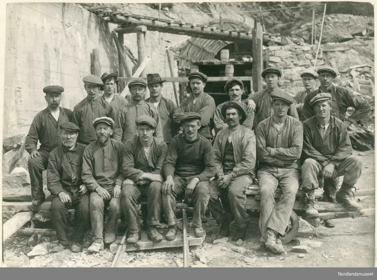 17 arbeidskarer foran murt vegg, tunnelåpning og stillas. Arbeidslag på Dovrebanen ca. 1915