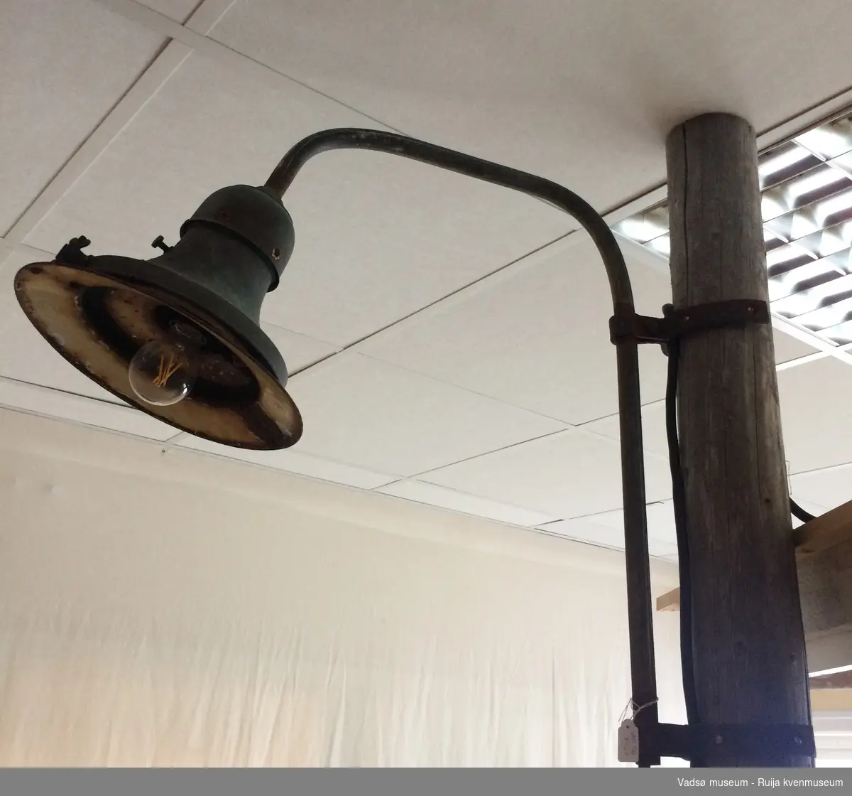 Gatelampe med grønn lampeskjerm. Lampa har mye rust, og den har betydelige skader på skjermen.
