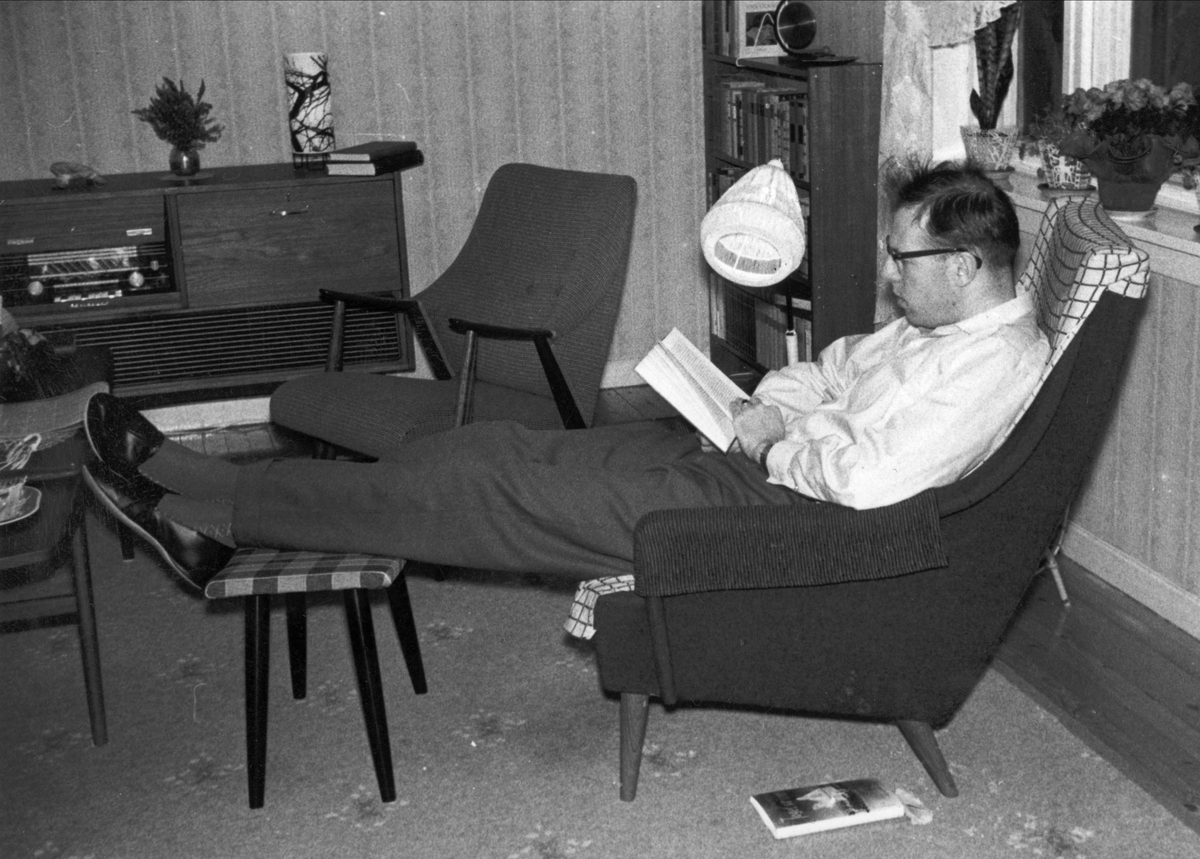 Mann leser en bok mens han sitter i en lenestol. Leiligheten på Sellebakk utenfor Fredrikstad.
