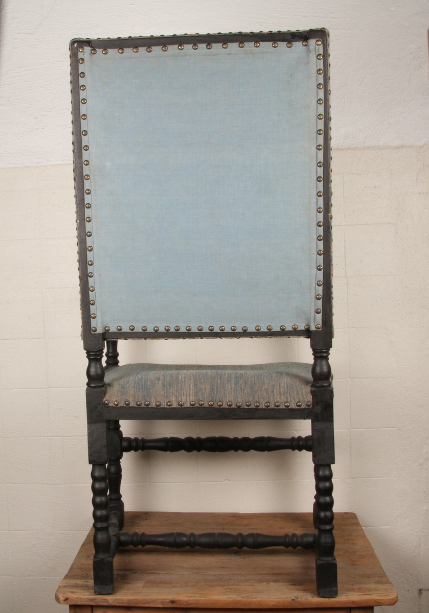 Stolen har høy rygg, dreide bein og tverrtrær sortmalt og blågrått trekk i stol og rygg.