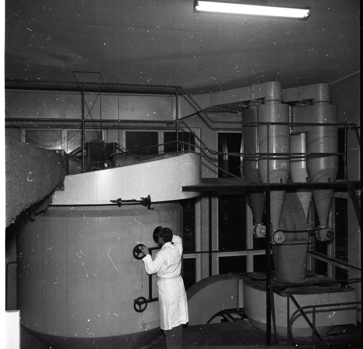 Interiör från livsmedelsindustrin AB Sprayprodukter i Gränna. Troligen fabrikör Jan Campbell som står på golvet och kikar in i en rund cistern.