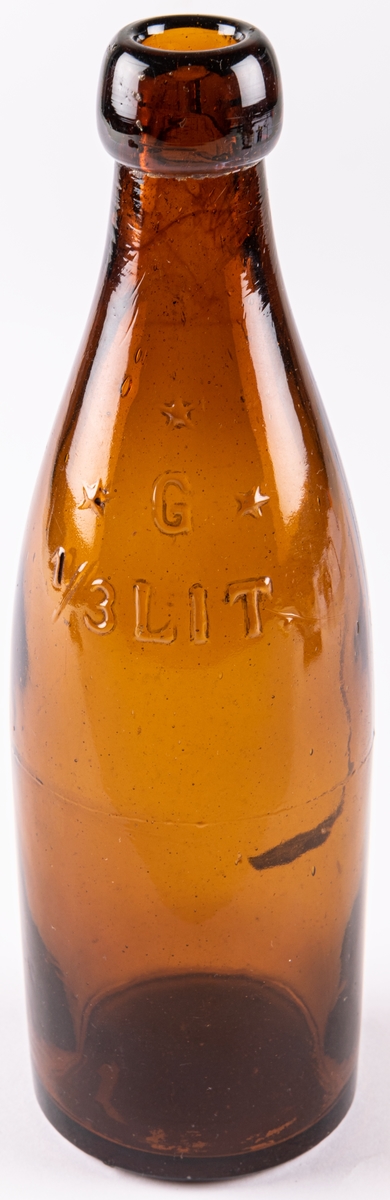 Butelj, så kallad "halva öl". Brunt glas. Märke i relief på sidan:
G (omgärdat av 3 stjärnor)
1/3 Lit.