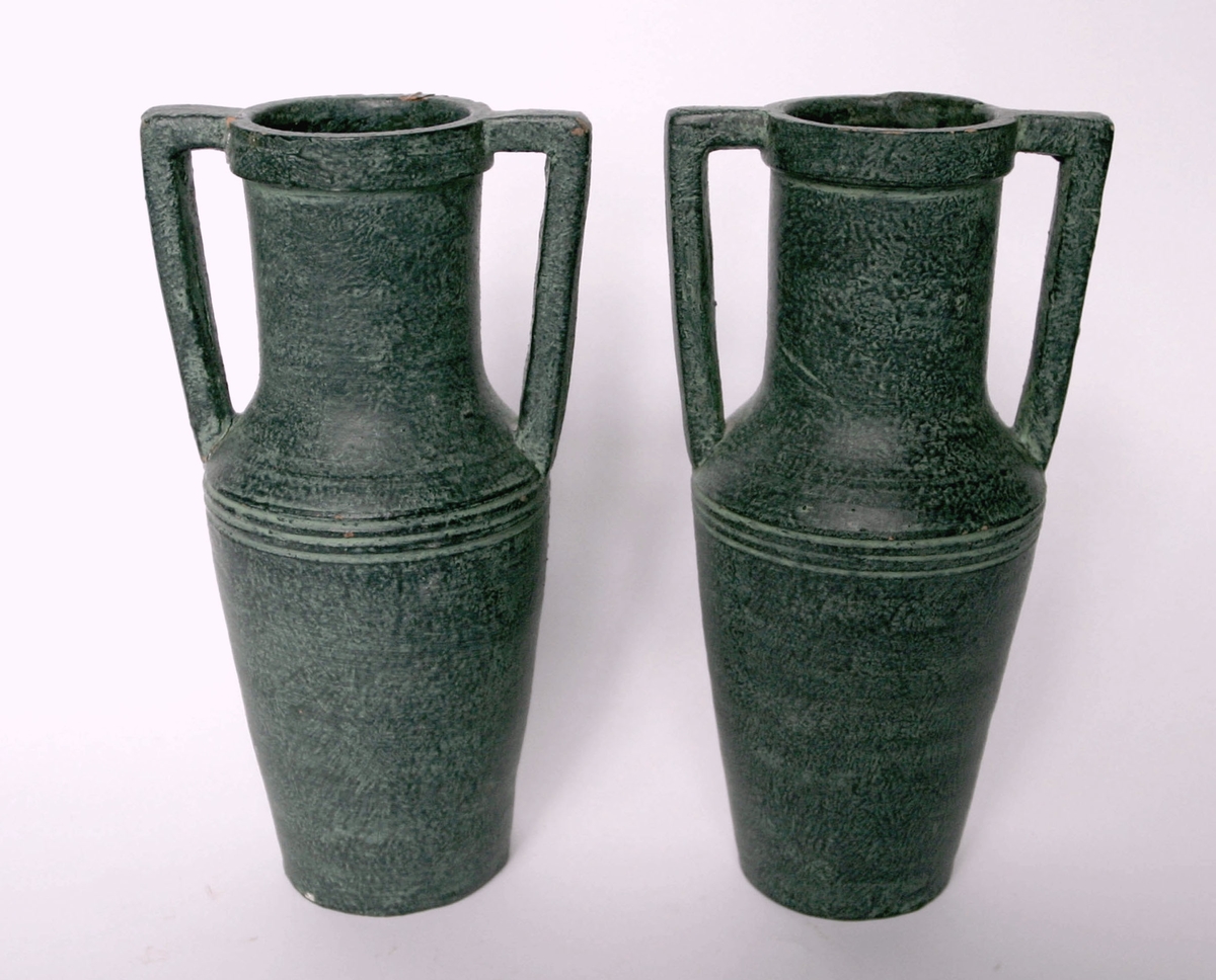 Två urnor (vaser) med hänklar, grönpatinerade. Tillverkade vid Bo Fajans, Gävle.