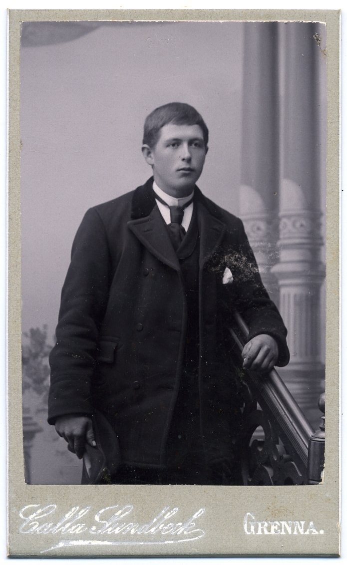 Kabinettsfotografi: porträtt okänd ung man med uppknäppt rock. Han håller en keps i höger hand.
