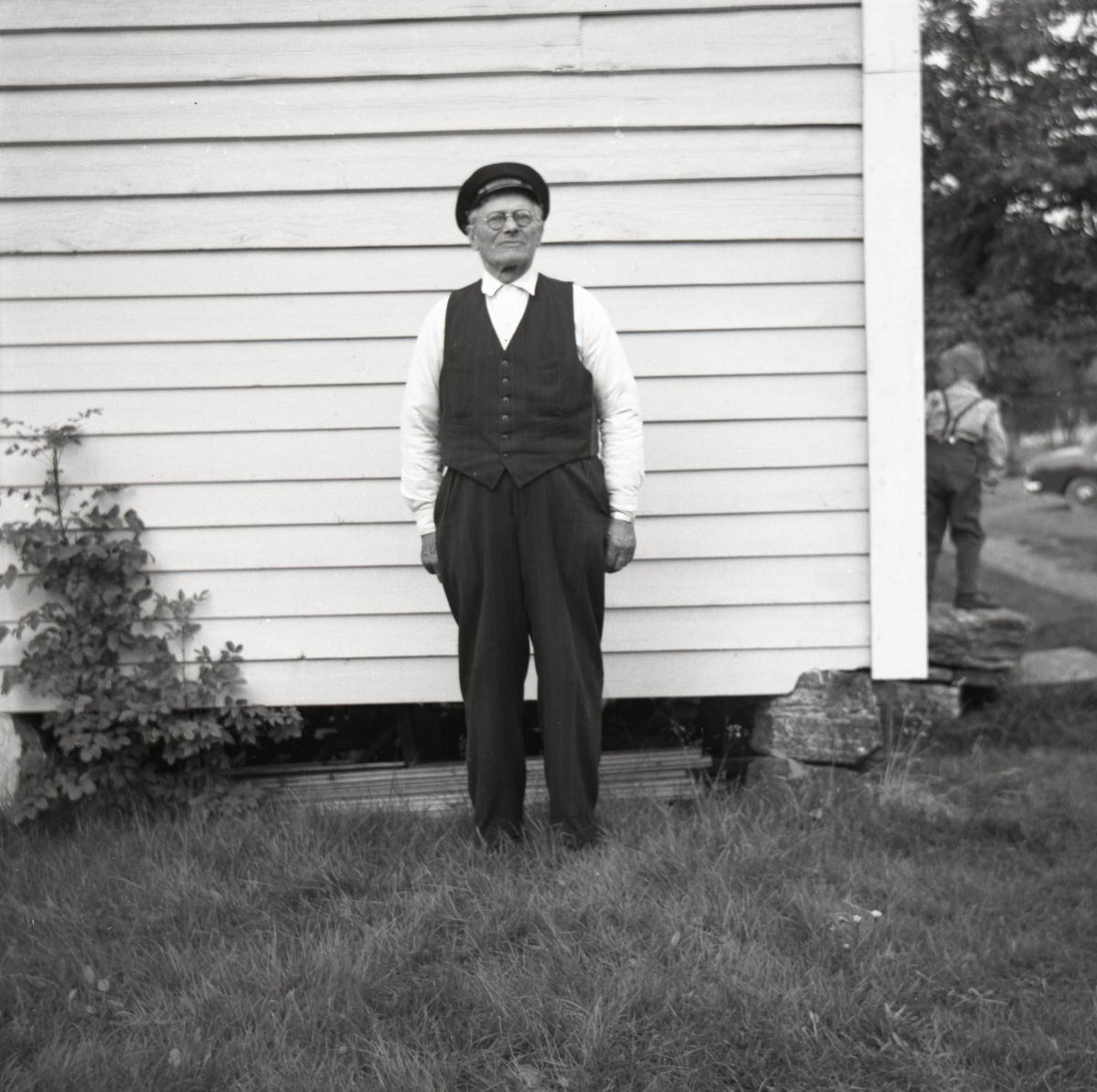 Portrettfotografi av en mann utenfor en husvegg.
