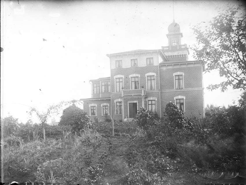 Större bostadshus med torn i trädgård, ca 1910.