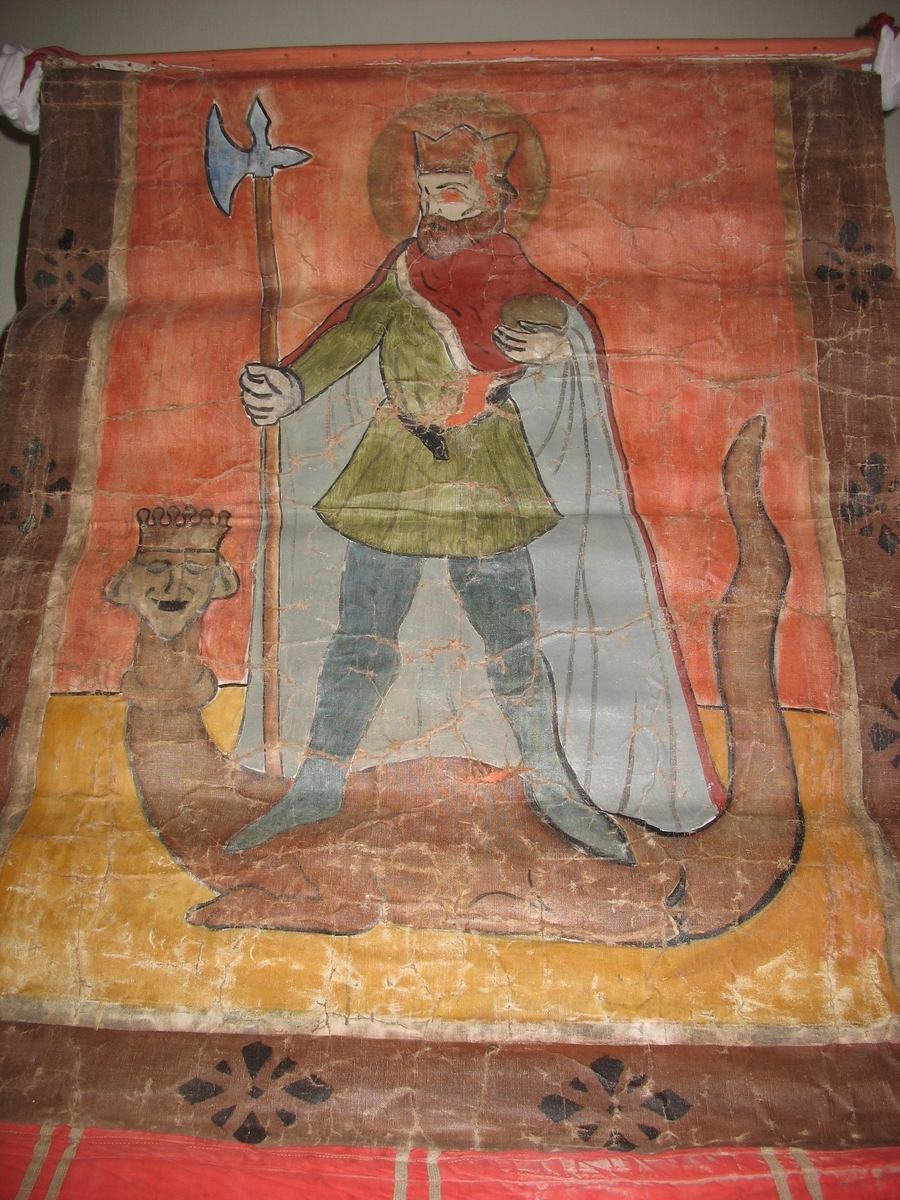 Øvre del: :Olav Haraldsson med krone, kappe og øks, som står på en "underligger" formet som en drage med menneskeansikt. Nedre del: påsydde blomster