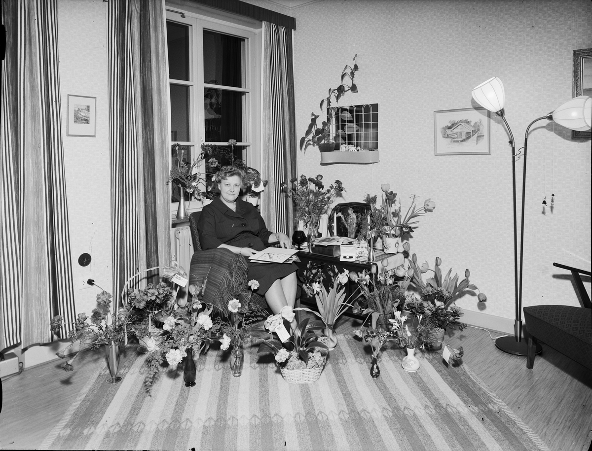 Kvinna i hemmiljö omgiven av blommor firar 50-årsdagen, Östhammar, Uppland