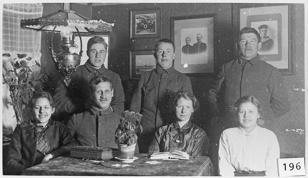 Menn på nøytralitetsvakt ca. 1918. Interiør med bilder på veggen, parafinlampe. 
