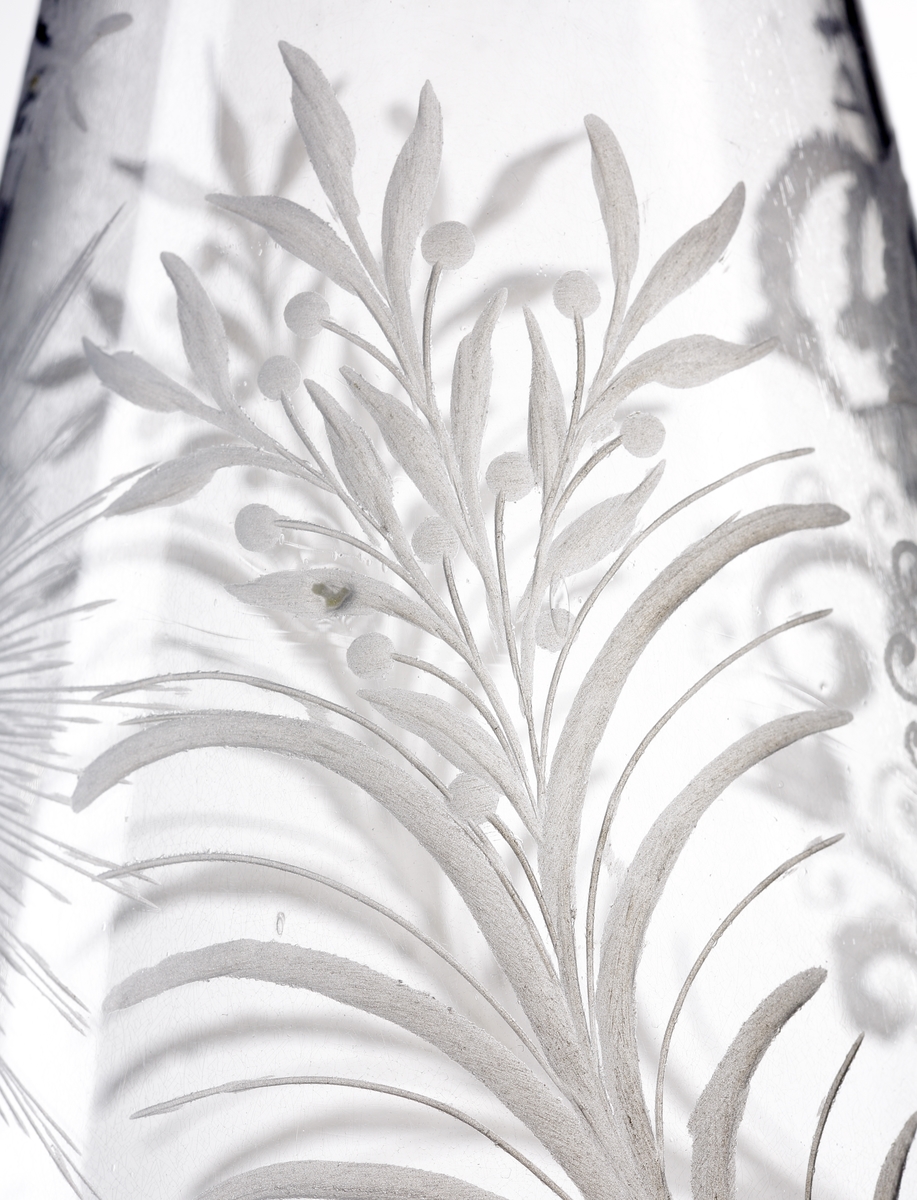 Vinkaraff, med halsring, utan propp. Graverat motiv i form av drottning Ulrika Eleonoras monogram under kunglig krona. Bred runtgående bladbård på hals och bål. Strålande nordstjärna på motsatta sidan.
Inskrivet i huvudkatalogen 1968.