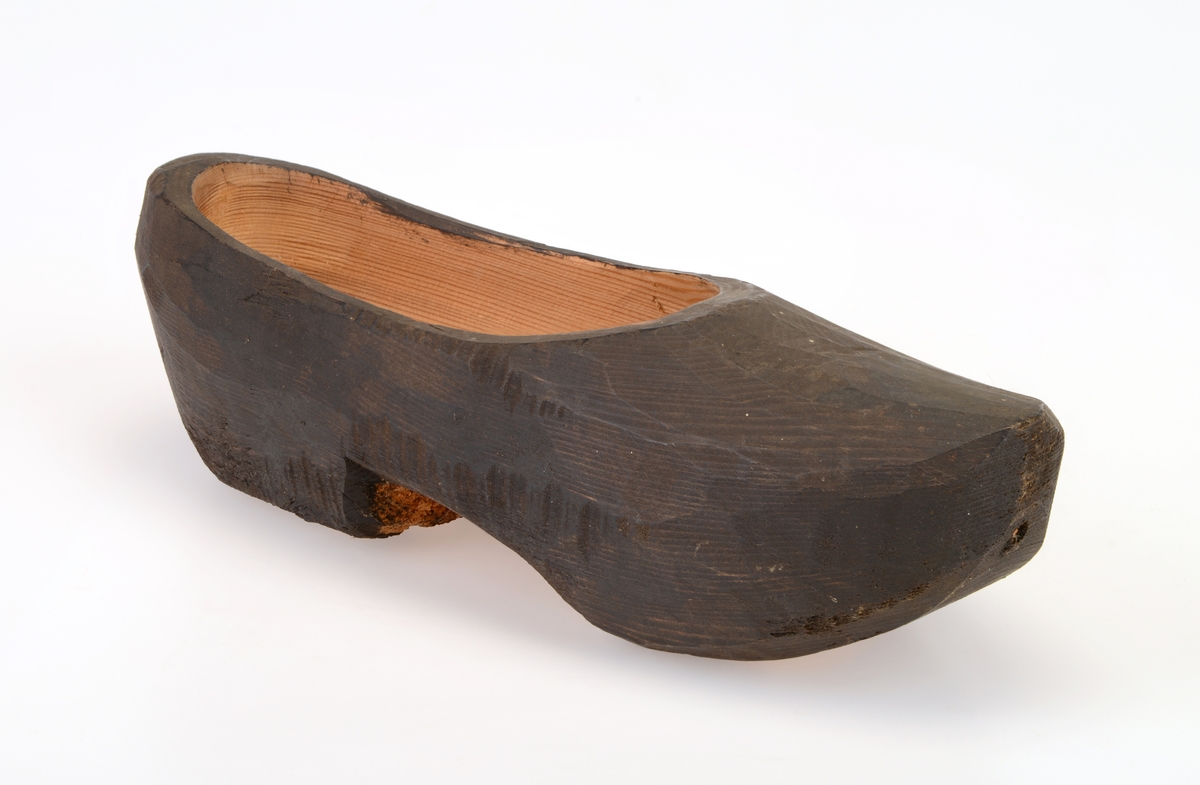 En tresko laget av ett trestykke (helskåret). Den er muligens laget av furu. De er trehvite innvendig og under. Utsiden er svartfarget, muligens etter at de er satt inn med tjære. Treskoen har hælkappe og foran er de spisse. Skoen har en lav hæl.
