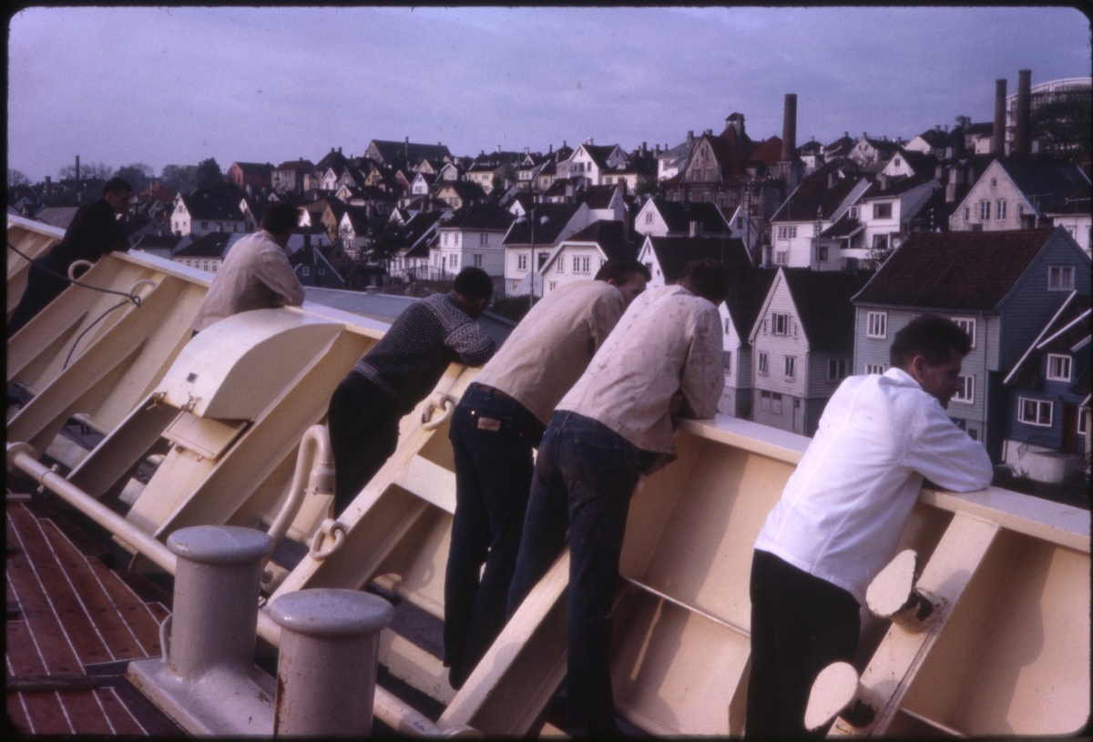 Passasjerer og mannskap om bord på cruiseskipet 'M/S Sagafjord' ser på trehusbebyggelsen ved Vågen i Stavanger, Norge. 'Sagafjord' Spring Cruise to Europe 1966.