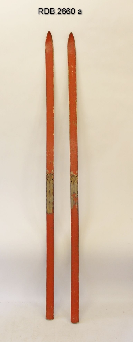 Et par rødmalte, jevnbrede helvedski uten bindinger. Lav skibrett. Malinga er ikke primær og er avslitt, På fotsteget er det 4 hull etter binding og flere stifter etter fotplate som er fjernet.