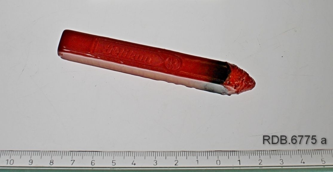Rektangulær blyantformet rød lakkstang, spiss i en ende etter å ha vært brukt.