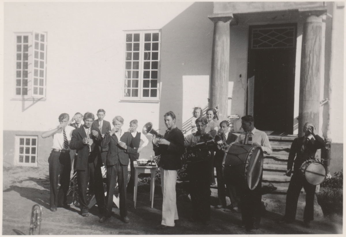 Festkledde gutter med instrumenter, fotografert ved murbygningen på Falstad skolehjem. Bildet er trolig tatt på 1930-tallet.