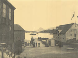 Bodø ca. 1905. Flere personer står på kaia. Utenfor ligger f
