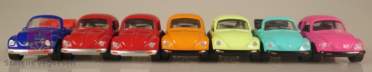 Samling av flere modellbiler. 2 biler er blå, 2 biler er røde, 1 bil er grønn, 1 bil er oransje og 1 bil er rosa. Alle er laget av metall og har en skala på 1:60.
