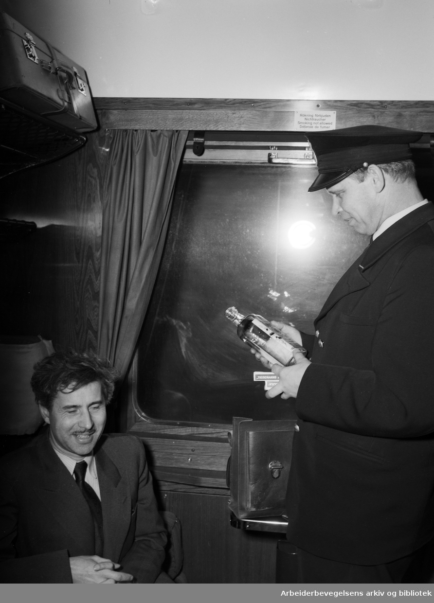Den svenske tolleren Fritjof Falckstrand (t.h.) sjekker bagasjen til togpassasjer Kaare Strøm, som er på vei fra Oslo til Gøteborg. (Professor og limnolog Kaare Strøm 1902-1967). November 1951.