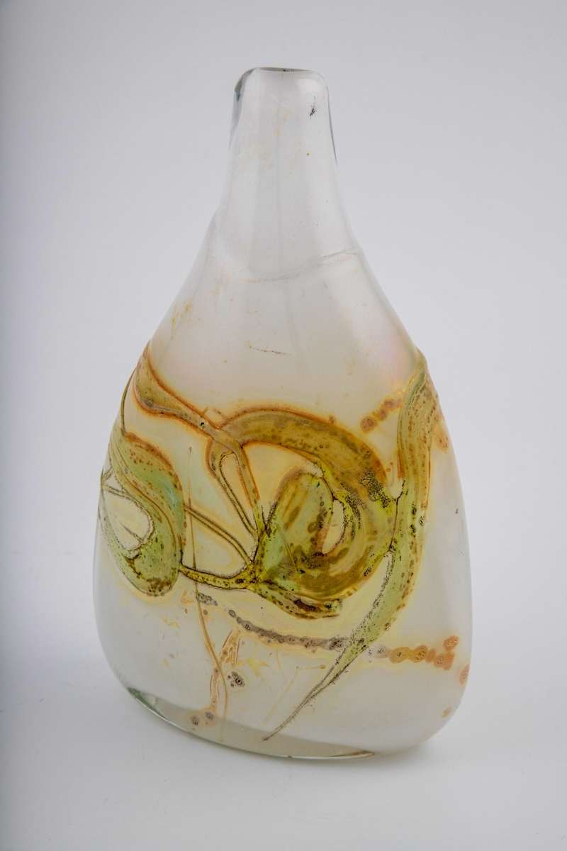 Flattrykket dråpeformet vase med lav hals. Vasen er utført i opakt melkehvitt glass i underfangsteknikk, med irisert overflate. Korpus er dekorert med slyngende gulgrønne partier, og hviler på en oval fotring.