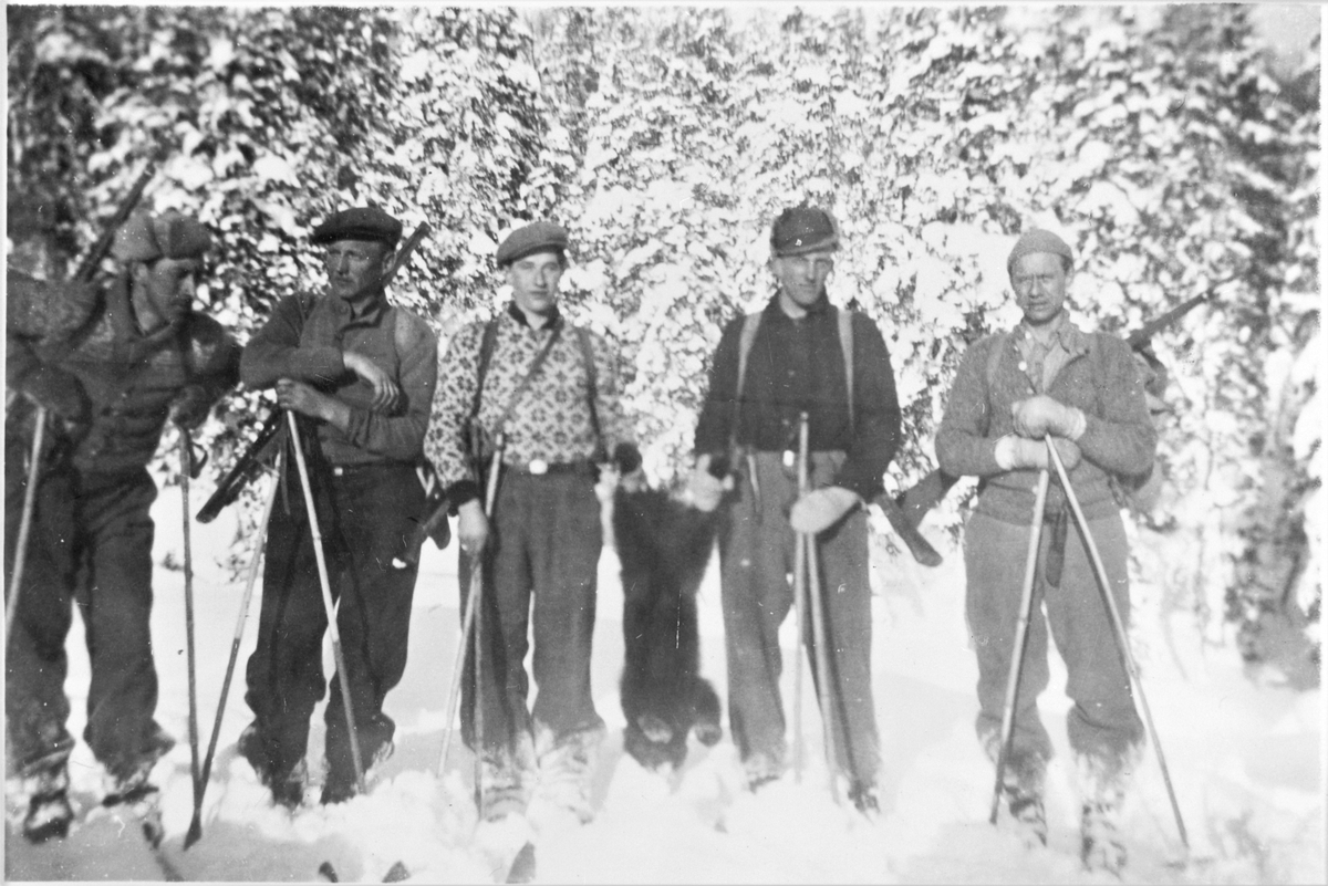 Vinterjakt, fem menn med gevær, på ski