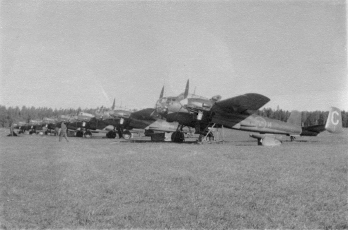 Flygplan Saab B 18 uppställda på flygfält vid F 14 Hallands flygflottilj, sent 1940-tal. Sex stycken flygplan står på linje..