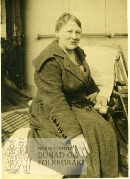 Kvinne i kåpe, sitter på en dekkstol (skip)
