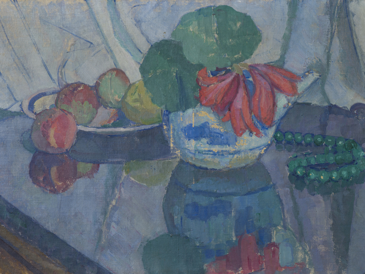 Fat og kanne med frukt og blomster er plassert på en blå flate med speiling. Et grønt perlekjede kan sees til høyre for kannen. 