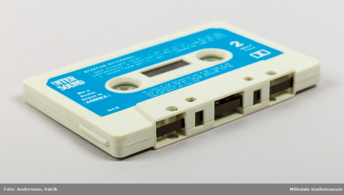 Ett kassettställ av hårdplast för förvaring av kassettband. Stället har en rund fot med manuell snurrfunktion. Kasettställets form är kvadratisk och färgen är röd. Ställets invändiga sidor är ljusgula. Hörnen har en vertikal sida med plast i träimitation. Kassettstället innehåller plats för 20 kassetter. I detta ställ finns 8 kassetter. På ställets ovansida finns en något upphöjd svart cirkel. Inuti cirkelns mitt finns en guldfärgad text med namnet Audio master.
Kassettband introducerades på marknaden 1963 av det nederländska teknikföretaget Philips. De användes för att spela in musik och talinspelningar. Kassettbanden var väldigt populära mellan 1975-1995.