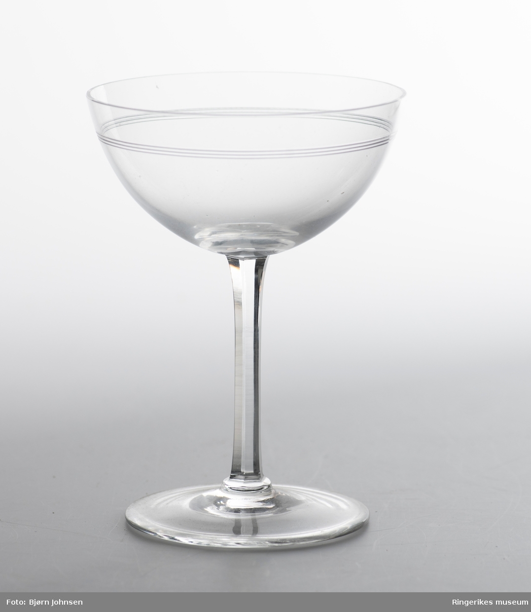To champagneglass med sekskanta stett. To tynne og tette slipte striper øverst på glasset.