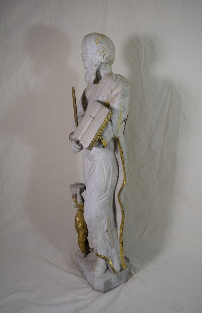 Evangelisten Matteus, stående på høyre ben med engelen ved kneet, oppslått bok på venstre arm. Kappen danner bakgrunn for figuren.