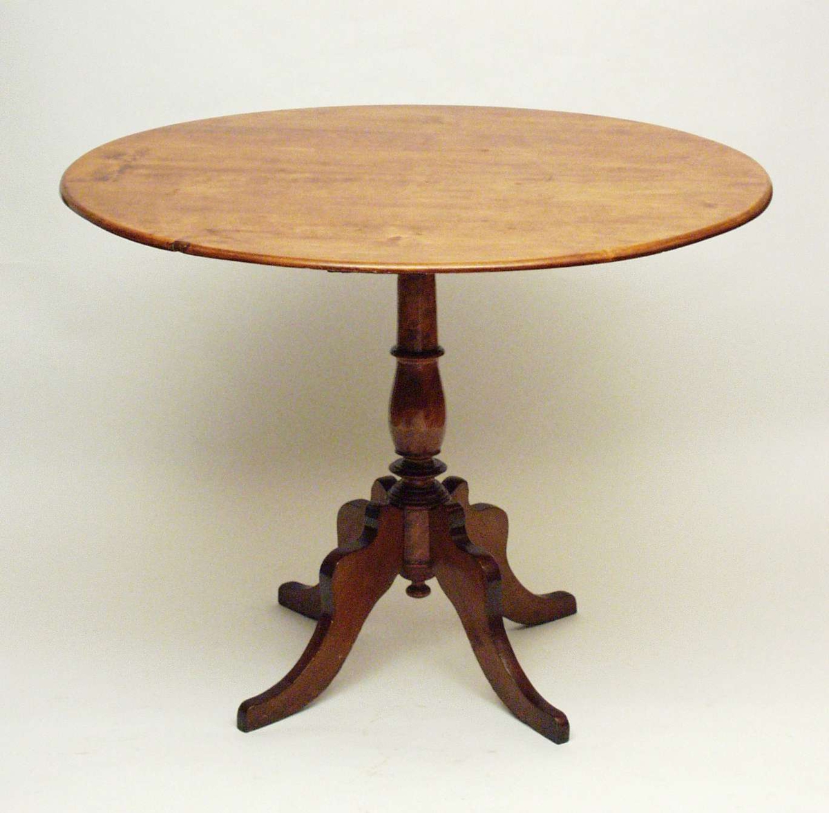 Bord i bjørk med rund plate, båret av en rund, profilert midtsøyle. Til søylen er det festet fire ben som svinger utover