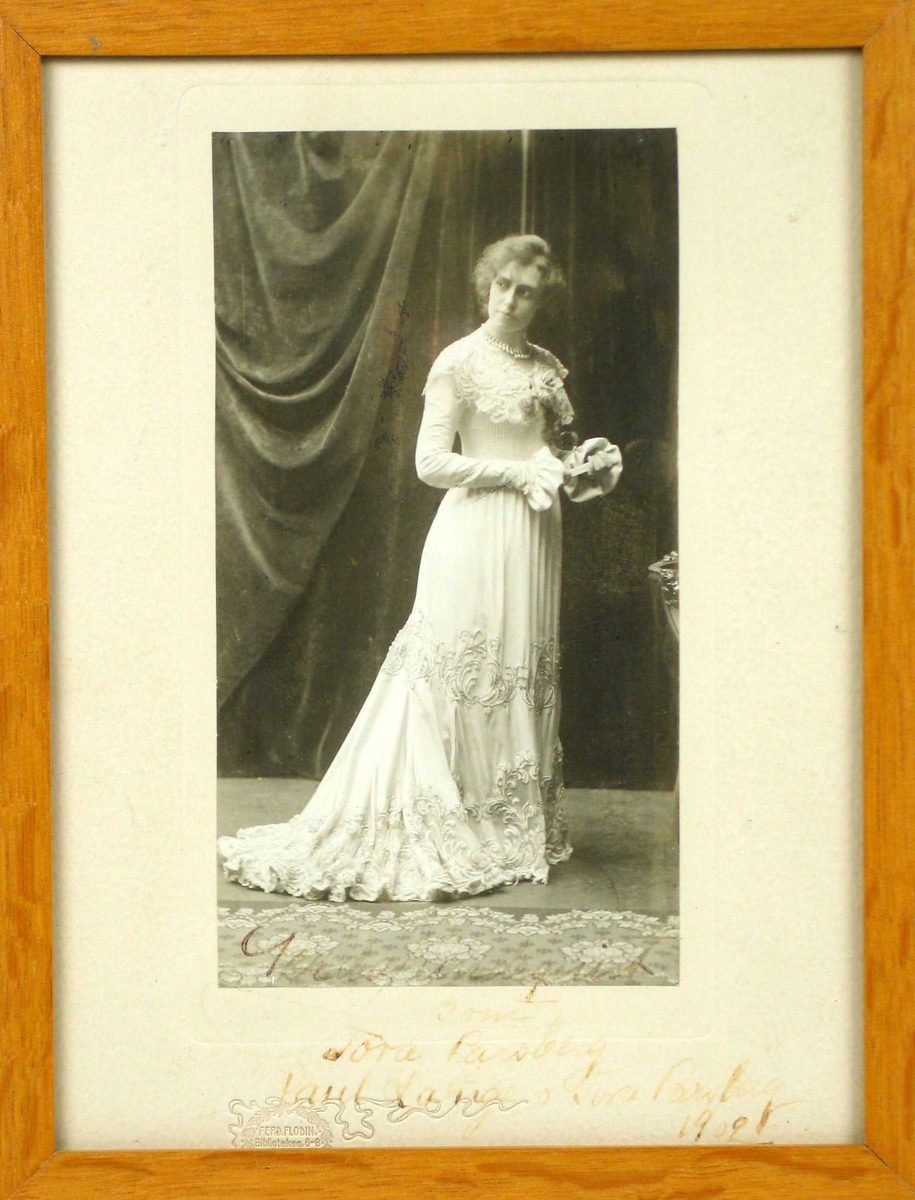 Scenebilde av en ung kvinne i lang lys kjole.