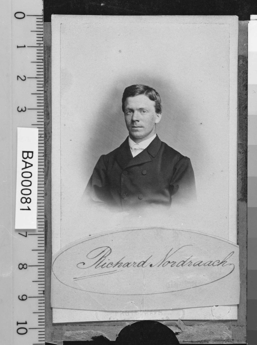 Portrett av ung mann i mørk jakke med hvit skjorte.