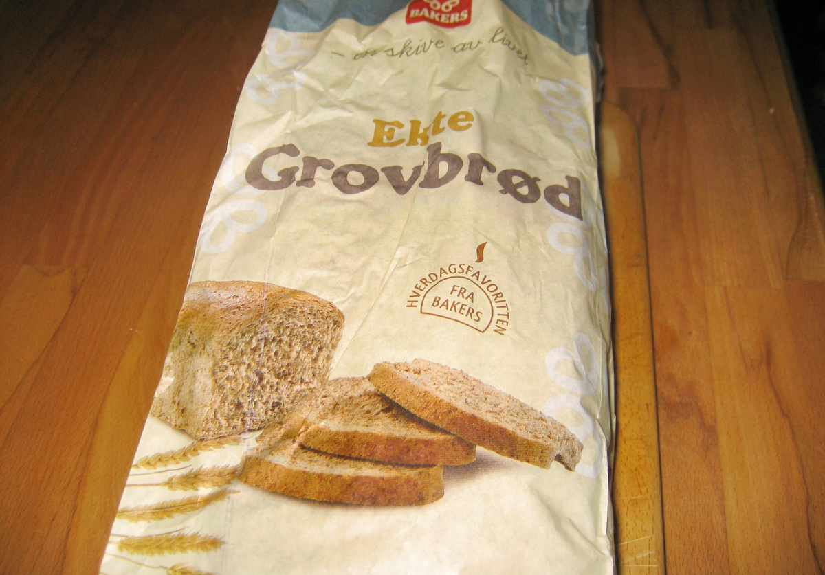 Motivet på brødposen et brød med tre oppskårne brødskiver og noen kornaks