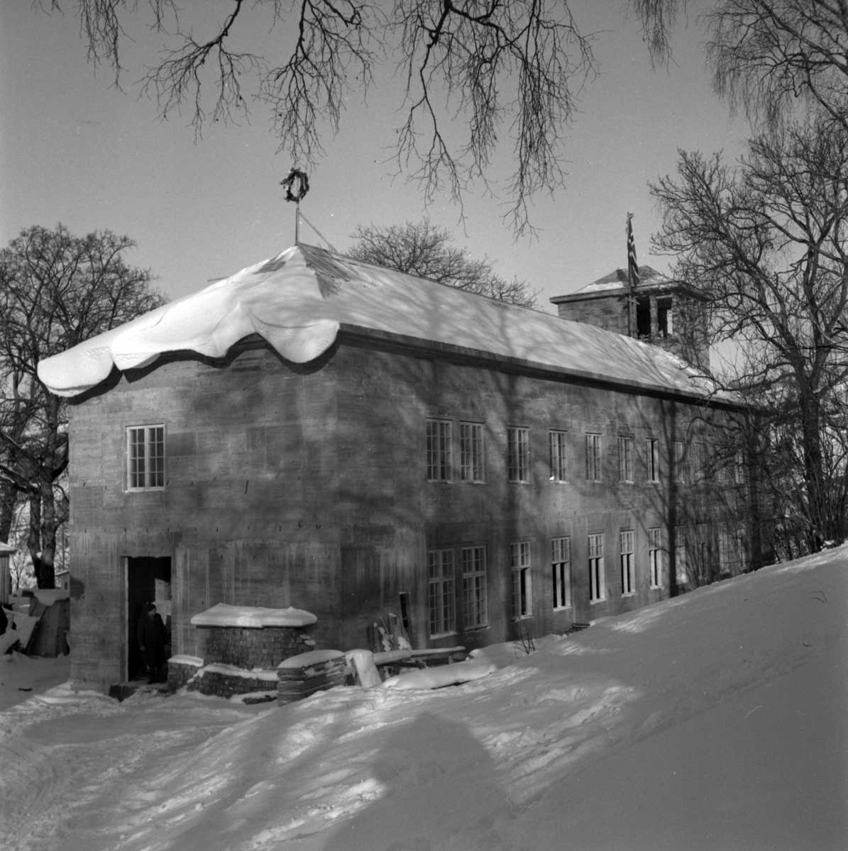 Aust-Agder-Museets første byggetrinn  - senere arkivfløy -  på Langsæ.  Kranselag. Vinter med snøl. Mennesker i døråpningen.