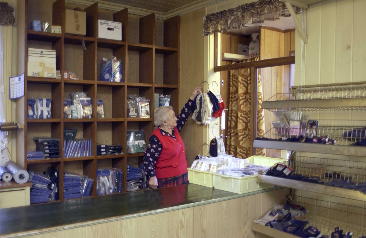 Manufakturbutikk, Marit Brubak-Vandås bak disken i ferd med å hente ned ragsokker,  interiør, varehyller