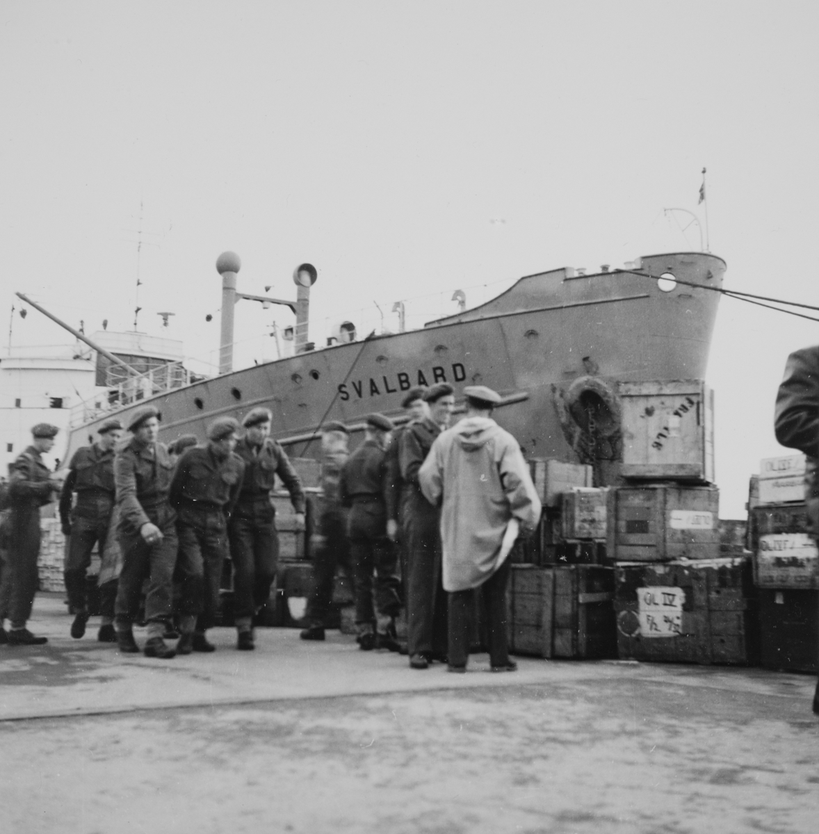 Soldater og forsyninger på kaien, med "Svalbard" i bakgrunnen. Se også FMU.403046.