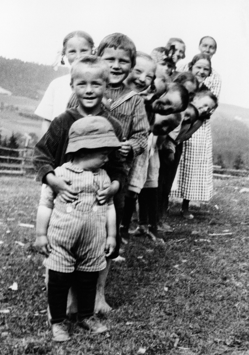 Gruppe barn på rekke. Julie Andreassen, mor til Alf Prøysen bakerst, nummer 8 er Alf, gutten med hatt foran er bror til Borghild Monsbakken, Præstvægen, Ringsaker.