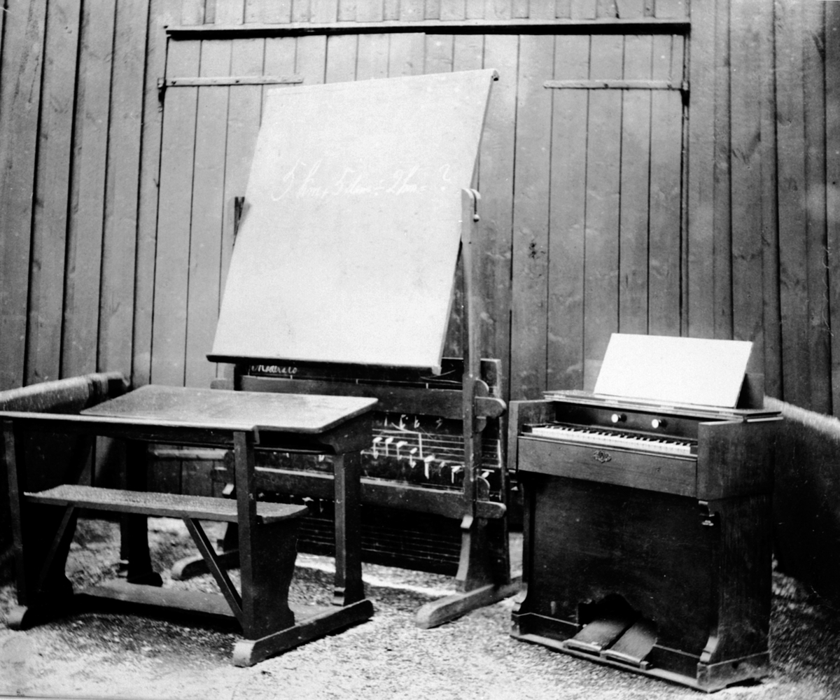 Klasserom for musikkundervisning på Toftes Gave, Nedre Sund, Helgøya med tavle, pult og orgel.