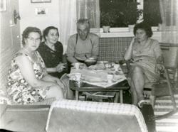 Fire personer sitter rundt et kaffebord inne