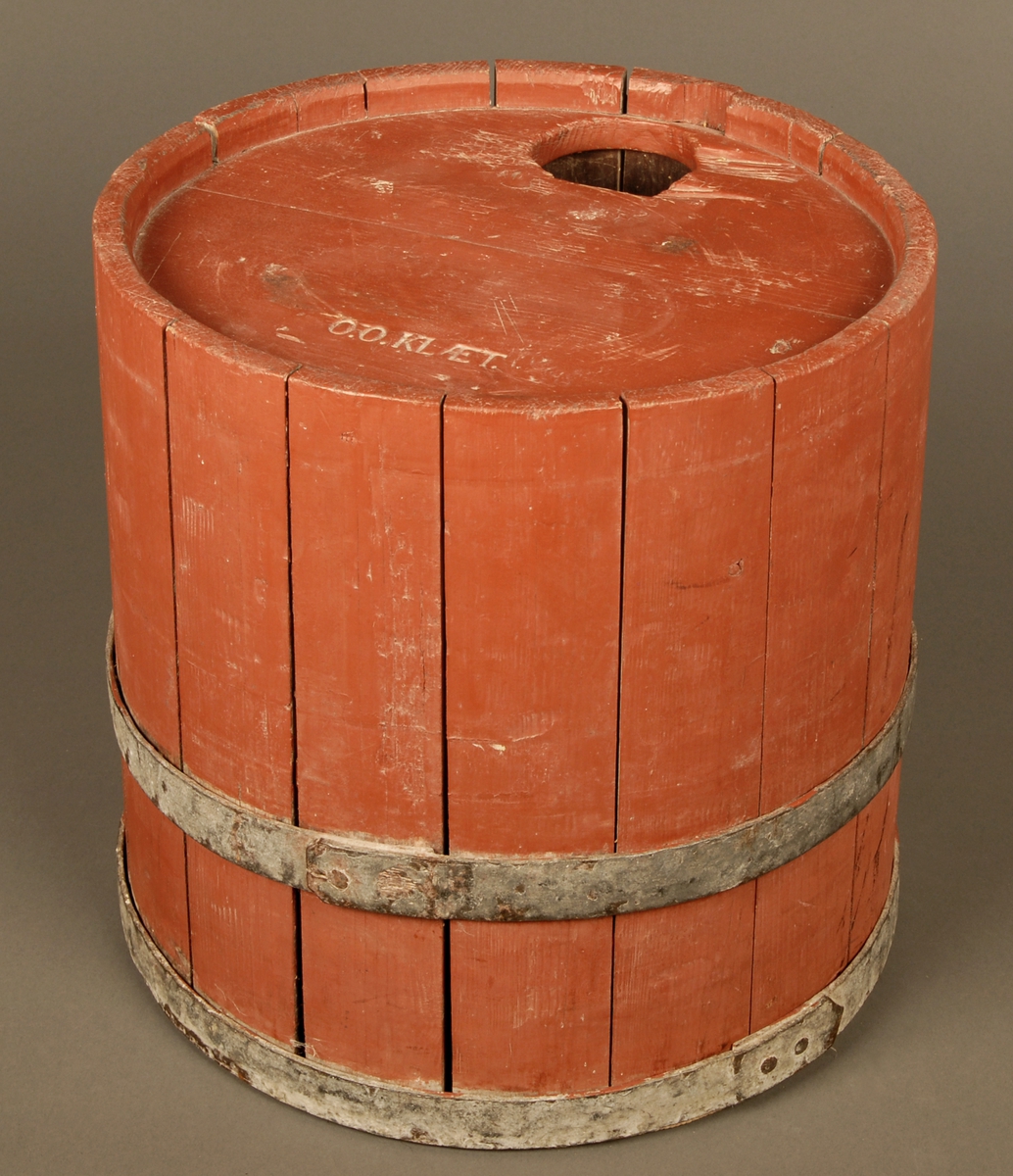 En rødmalt bøkret tretønne med to band av jern. Et hull på cirka 8cm i diameter på topplokket. Påskriften O.O.Klæt.