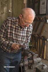 Smeden Oddbjørn Knudsen filer vedåpningen i ei merkeøks.  Fø