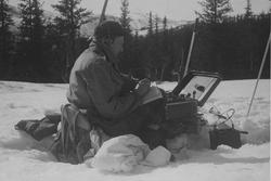 Claus Helberg sittende i snøen med radiosender/mottager uten