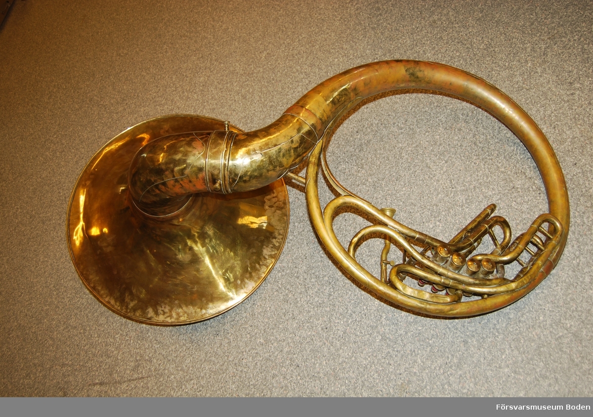 Äldre sousafon (bastuba för marscherande musiker) av mässing. Ingen märkning kan hittas. Har sannolikt använts vid musikkår i Boden.